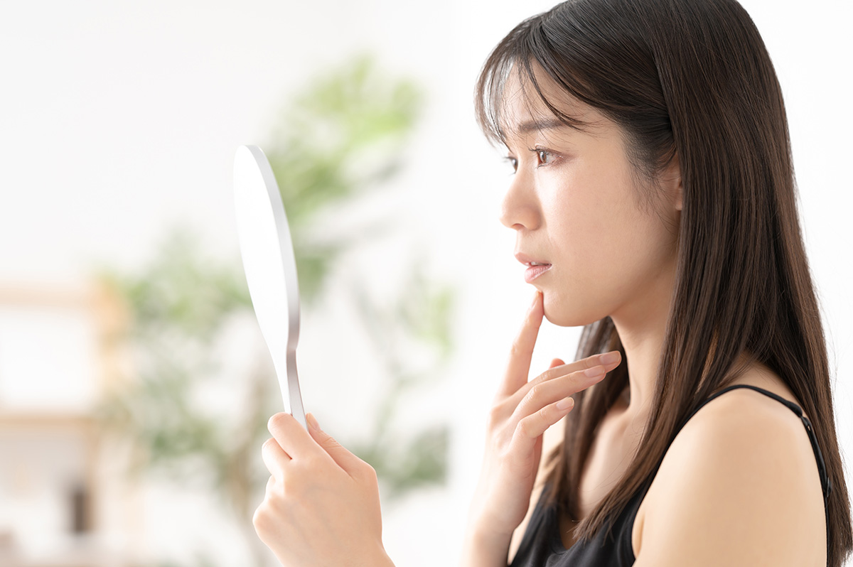 手鏡を見て考える女性
