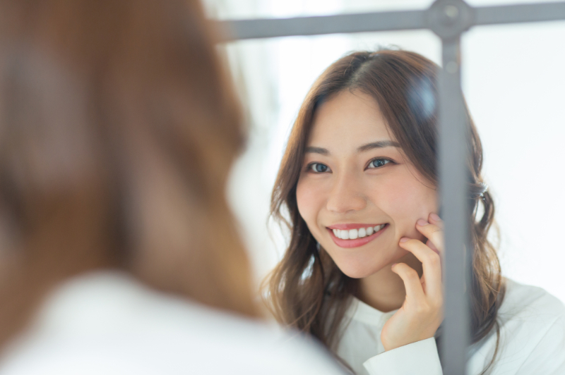 白くなった歯を鏡で確認する女性