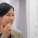 鏡を見て歯周病を疑う女性
