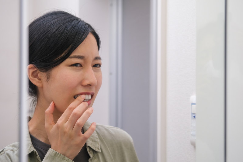 鏡を見て歯周病を疑う女性