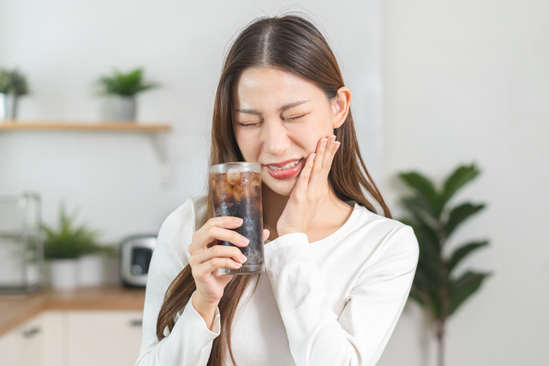 虫歯ができて冷たい飲み物がしみる女性