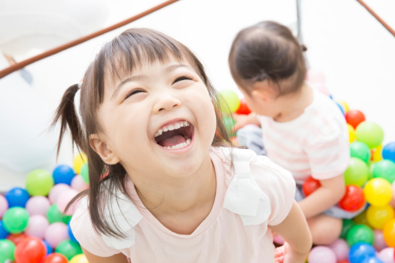 笑顔で楽しそうにボールプールで遊ぶ女の子