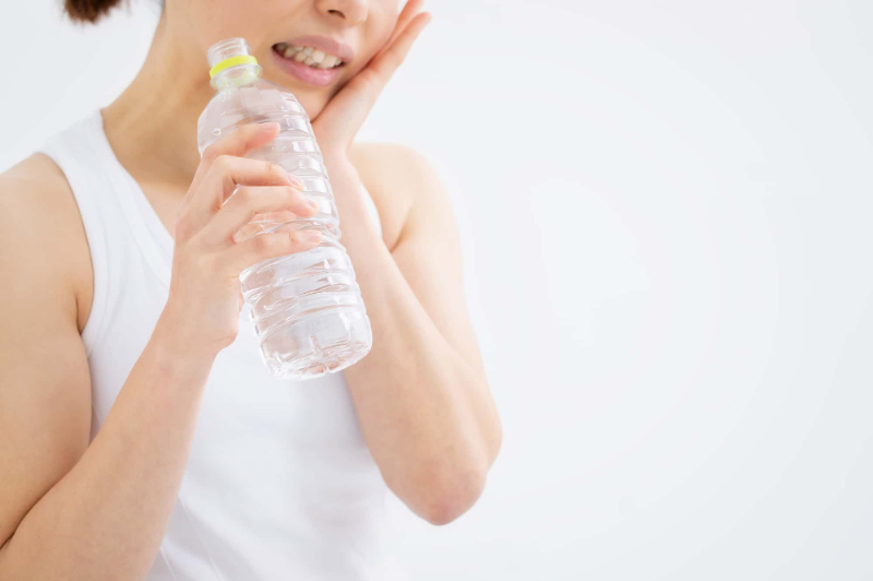 歯と歯の間に虫歯ができて冷たい飲み物がしみるイメージ