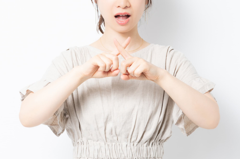指でバツを作る女性
