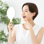 詰め物が取れた歯を鏡で見ている女性