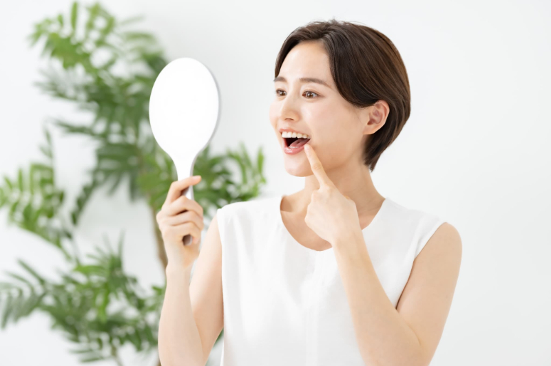 詰め物が取れた歯を鏡で見ている女性