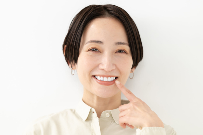 ホワイトニングをした白い歯を満足気に指さしている女性