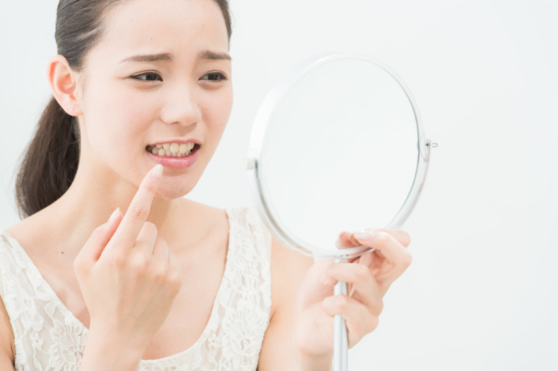 マウスピース矯正後の歯ならびが気に入らなくて鏡を見る女性